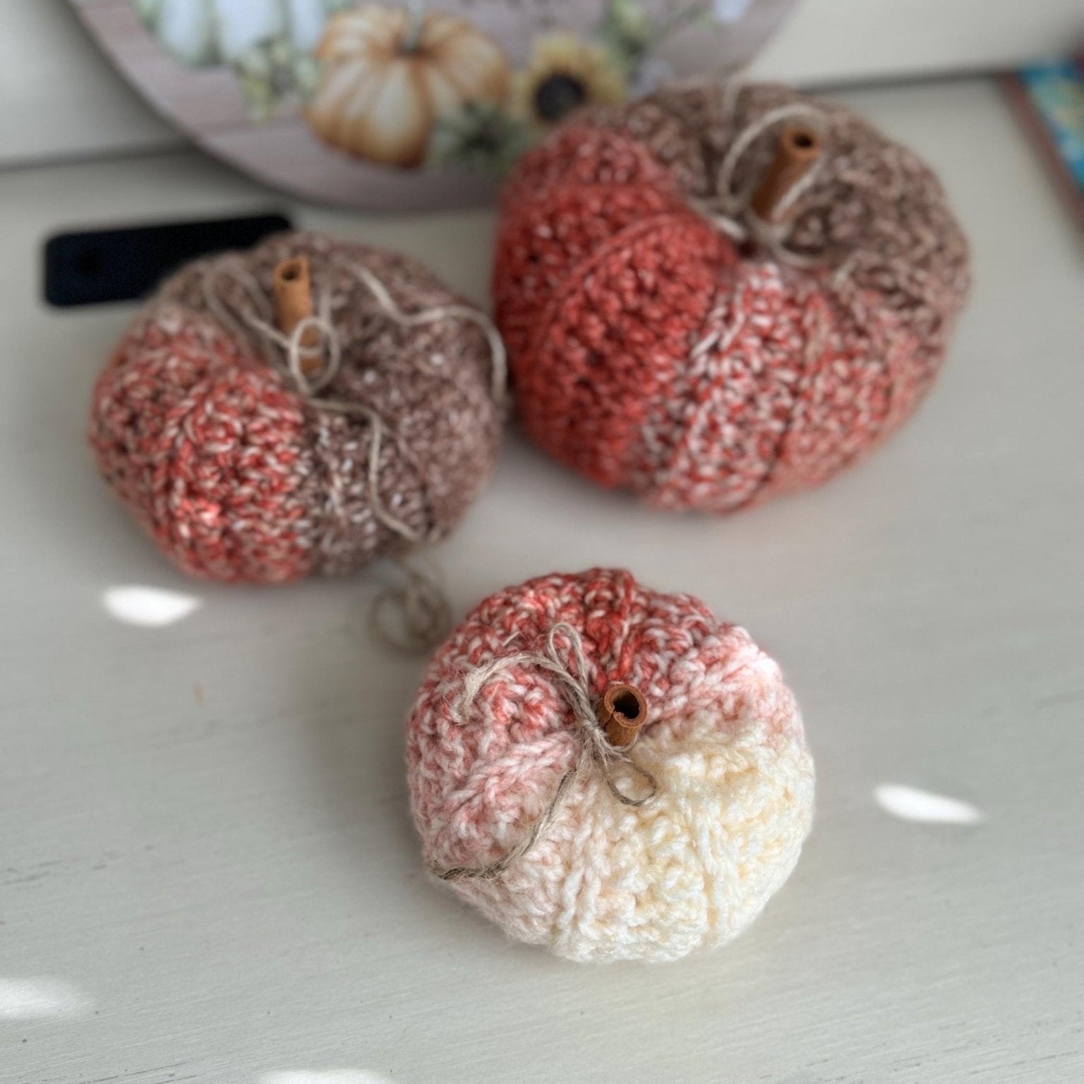Three crocheted pumpkins, small, medium, and larger size in fall colors mix of orange brown and beige
