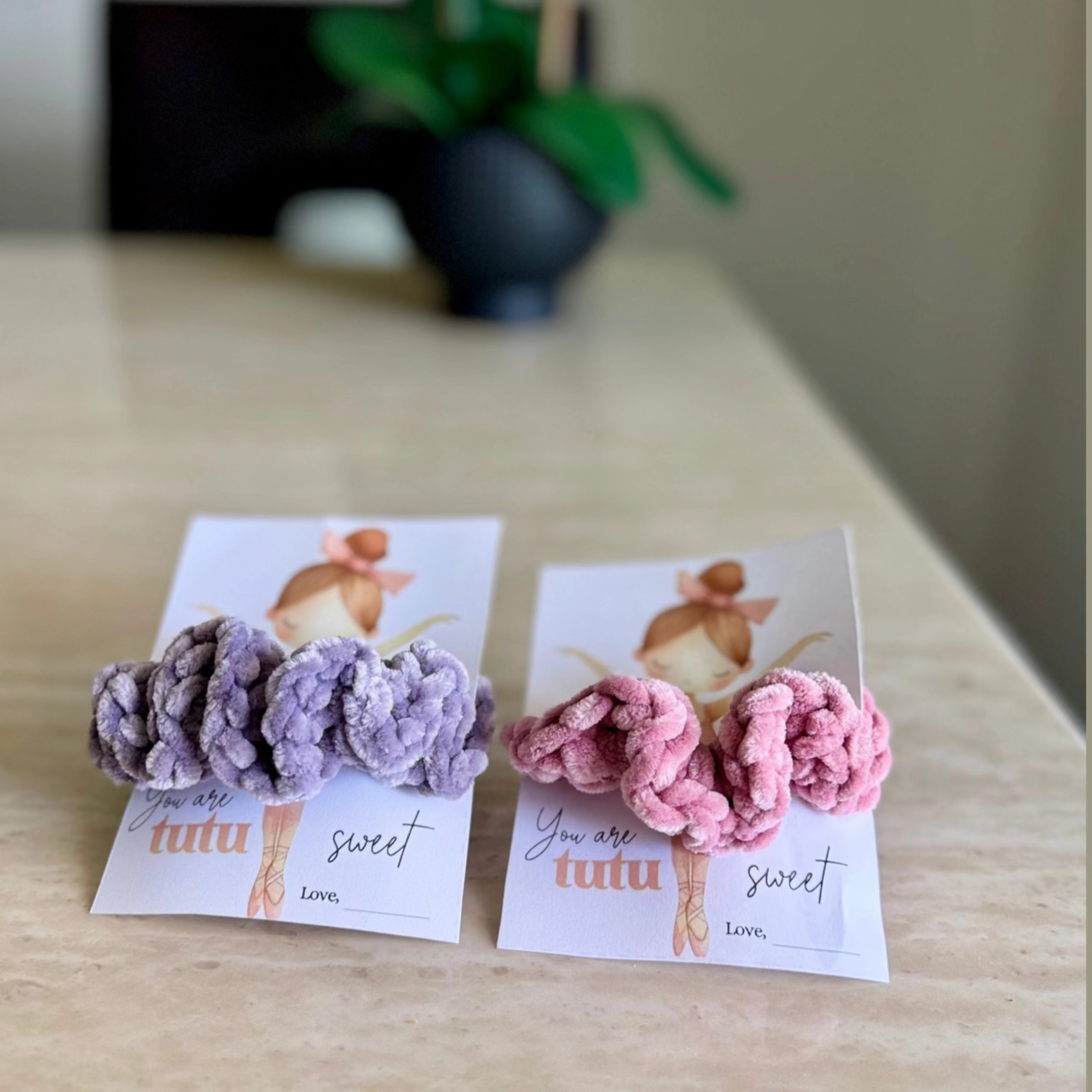 Two hair scrunchies - one pink and another in purple- on the cute holder card with little ballerinas which has a sign "You are tutu sweet"