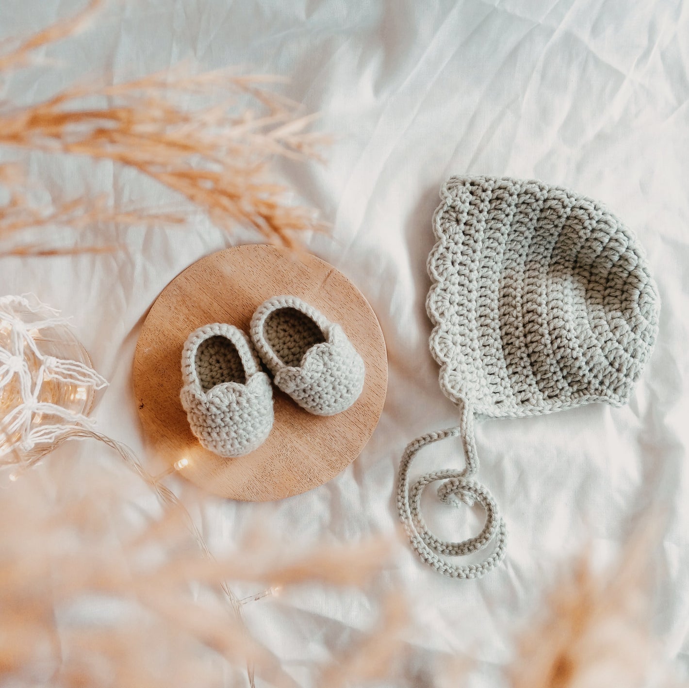 Crochet baby booties and crochet bonnet on the beautiful neutral background